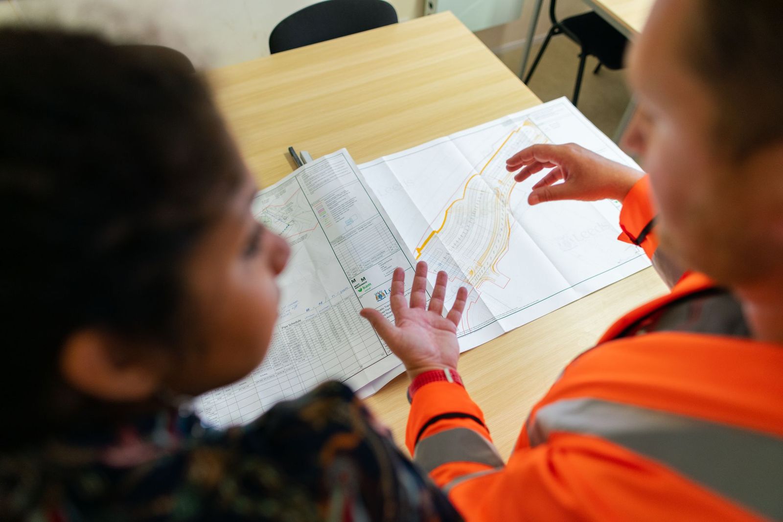 Two people reviewing a set of drawings together across a table