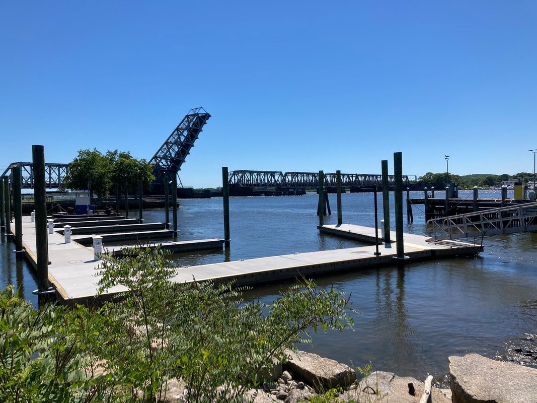 Floating docks and pilings with the Connecticut River railroad bridge beyond