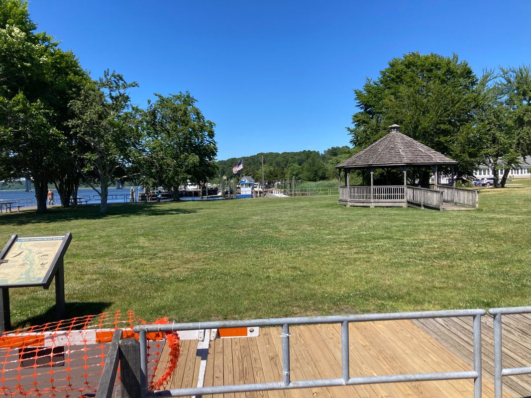 Lawn and gazebo at the marina waterfront, with temporary fencing at the dock access