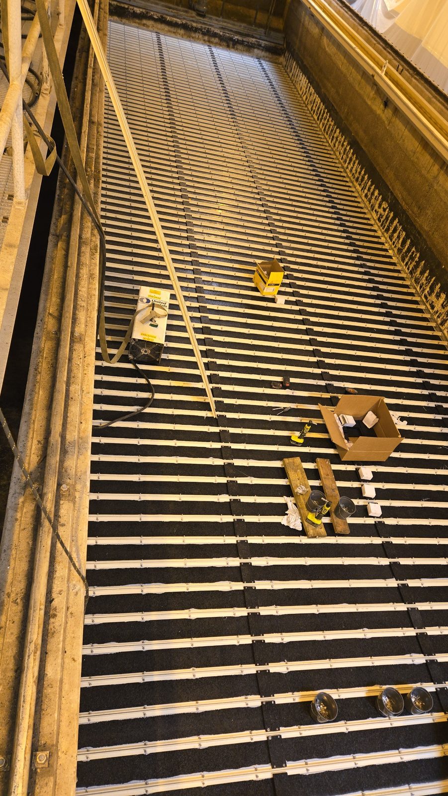 Globe Hollow Filter No. 1 dewatered during underdrain reconstruction, with new underdrain strips fastened across the filter floor and tools on the deck