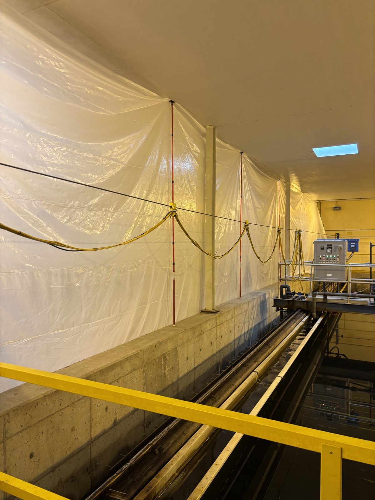Filter No. 1 back in water after media replacement, with poly protection sheeting still in place along the wall