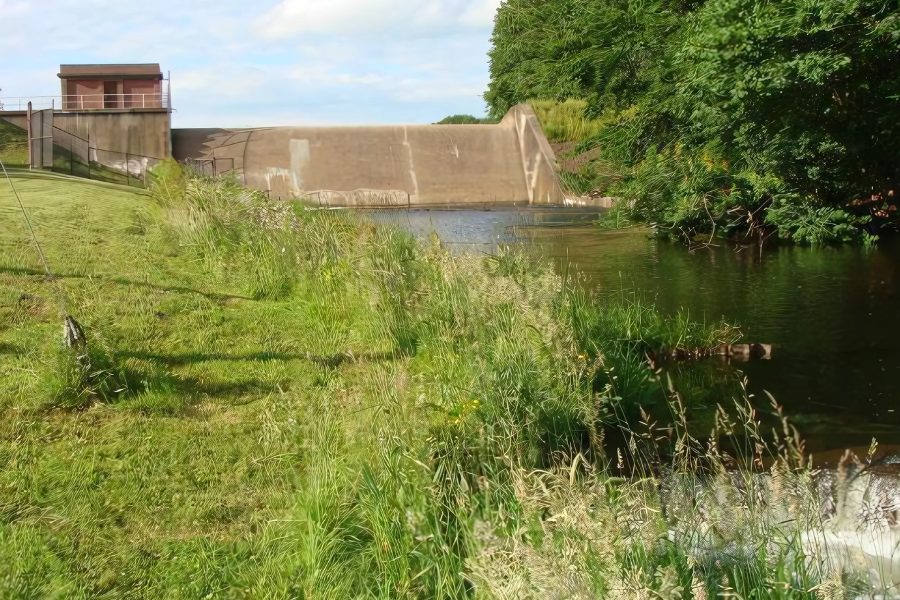 Mackenzie Reservoir dam spillway and gatehouse beyond a grassy bank