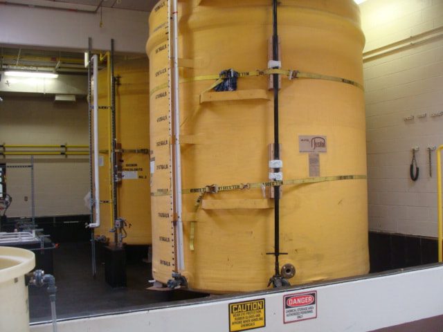 Yellow sodium hypochlorite storage tanks inside the containment wall