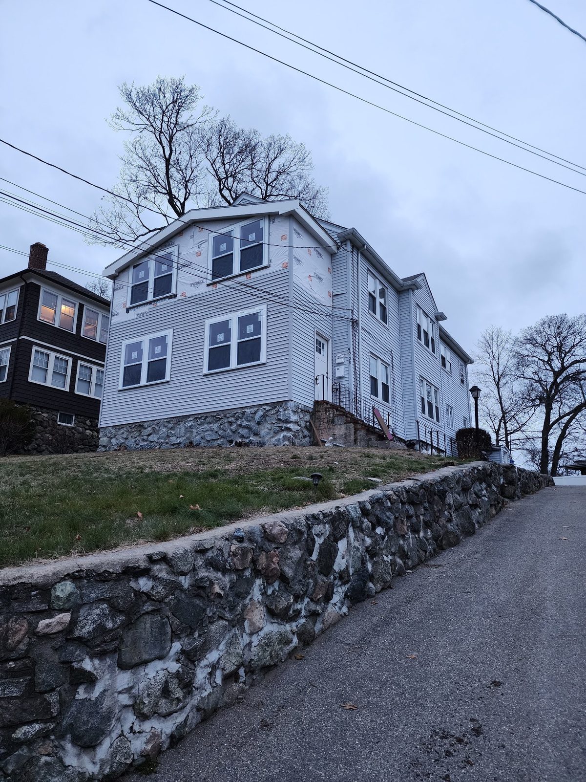 New two-story front addition with siding going on below and house wrap still showing above