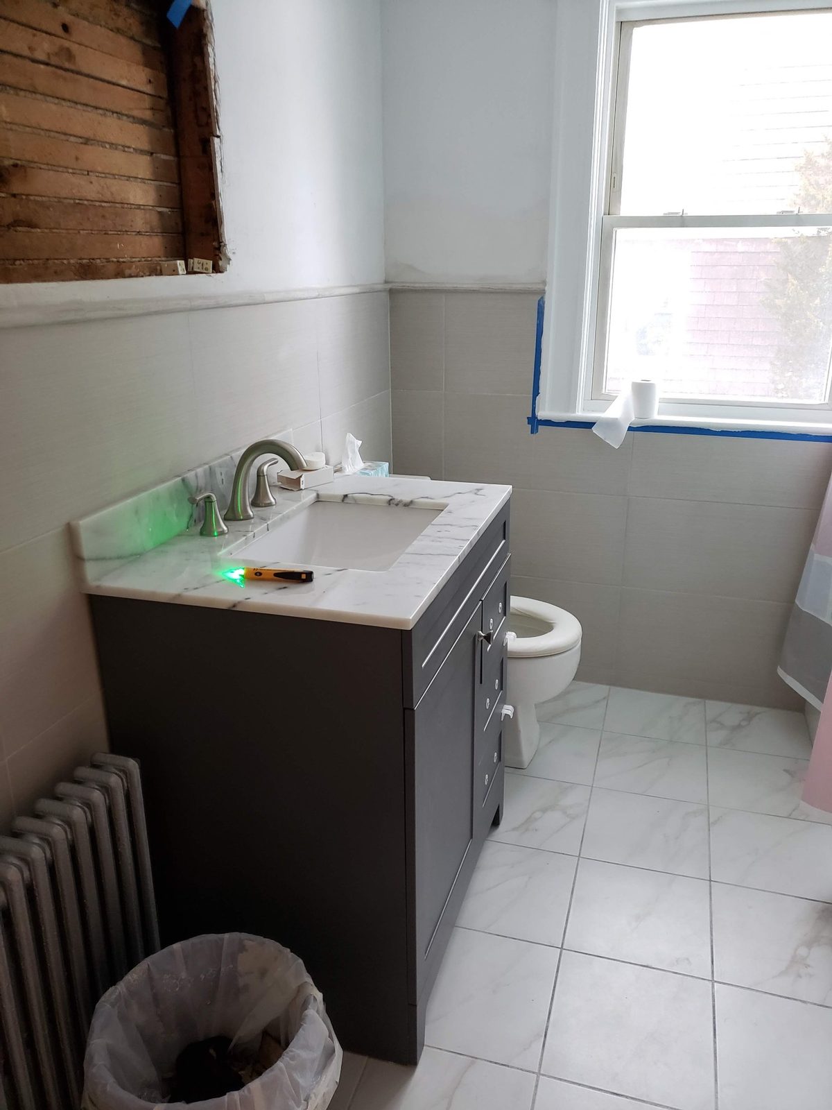 Renovated bathroom with large-format wall tile, marble-look floor tile and a new grey vanity with marble top